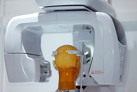 Cone-beam computed tomography system with a mannequin head surrounded by the imaging device.
