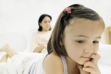 Fotografía de una niña con su mamá visible en segundo plano