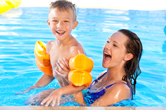 A boy plays in the pool with his mom.