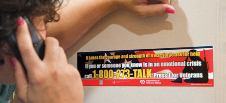photo of person on the telephone looking at a magnet with the number 1-800-273-TALK
