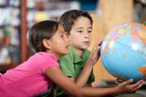 Two kids look at a globe together.