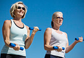 Two women lift weights together.