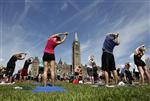 People take part in a free weekly yoga class on the front lawn of Parliament Hill in Ottawa July 25, 2012. The class runs every Wednesday from May through September. REUTERS/Chris Wattie