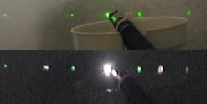 Photo from an ordinary camera shows light from a green laser diffracted into several spots. The green laser pointer is visible in the foreground. (Bottom) The same vignette photographed by a webcam with no infrared-blocking filter reveals intense diffraction spots from 808nm infrared light, invisible to the eye. 
