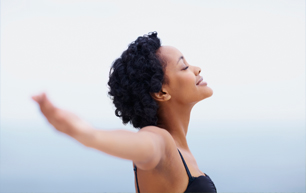 African American woman with her arms outstretched looking towards the sky