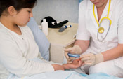 Health professional using glucose meter to prick finger of young girl