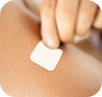 Transdermal nicotine patch being placed on arm.