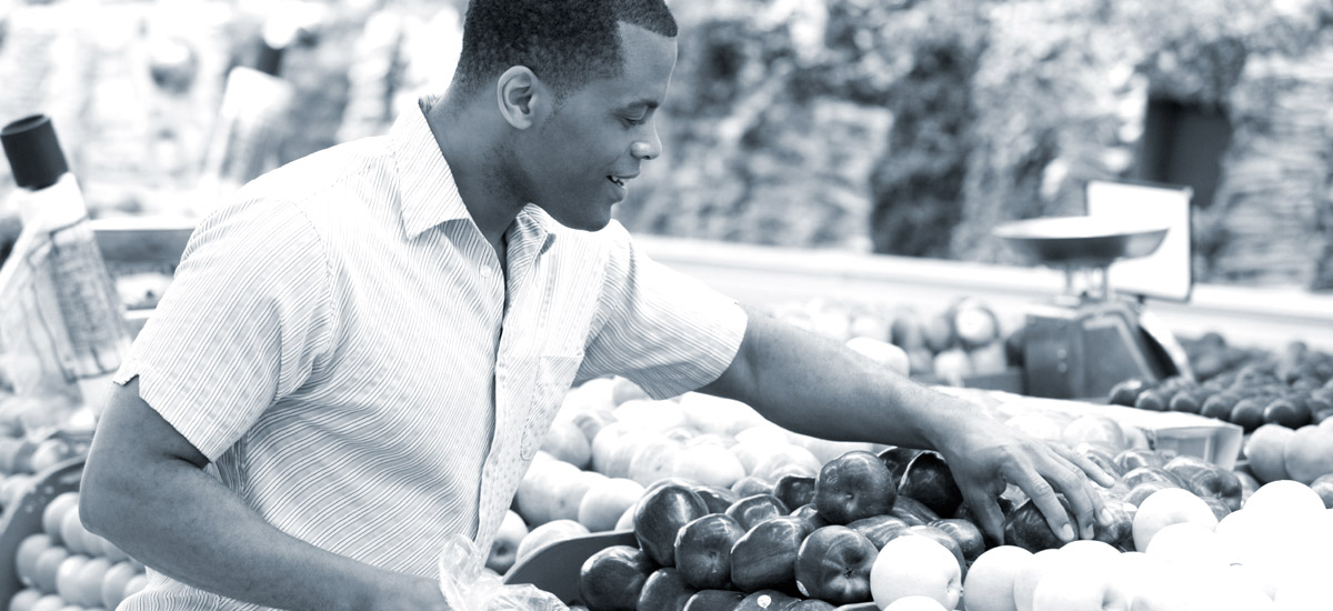 Photo of a man picking through produce at a grocery store