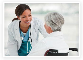 Una médica sonriente se inclina para hablar con una paciente en silla de ruedas