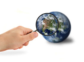 Hand Holding Magnifying Glass to a Globe