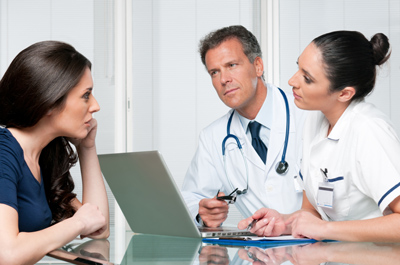 Female patient talking with a doctor and nurse.