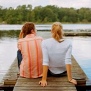 Two people sitting on a dock.