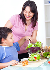 A mother serves her son a fresh salad.
