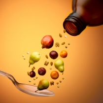 Fruit and nuts pouring from a vitamin bottle