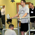 Photo of a standing man supported by hand rails and physical therapists.