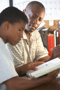 photograph of teenage boy doing homework with adult who might be foster parent