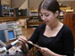 Image of a young woman holding a circuit board and next to table with electronics.