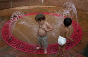 Two toddlers playing in an interactive fountain.