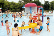 A water play area filled with parents and children.