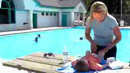 Idaho Dept. of Health and Welfare - Shower before Swimming 3 - Screenshot of a video showing a woman changing a baby's diaper next to the pool