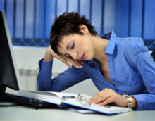 Photo of a woman nodding off at her desk.