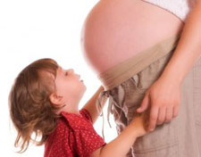 A boy holding his pregnant mother's hands