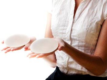 Woman holding a pair of breast implants in her hands.