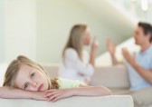 Sad girl with parents fighting in background