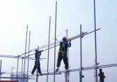 man wearing blue coverall and welding gear while working