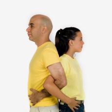 Photograph of a man and girl standing back to back with arms locked