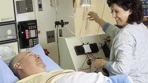 A health care provider is shown talking to a patient in a hospital bed.