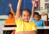 Children in classroom raising hands