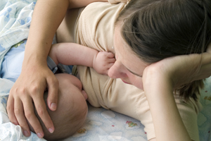 woman breastfeeding an infant while laying down