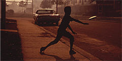 Tossing a frisbee on a smoke-filled street in North Birmingham, Alabama, July 1972.