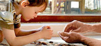 Image shows a boy and a man sorting through coins.