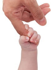 A young baby grabs his father's finger.