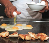 A chef cracks eggs on the stove