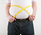 An overweight man measures himself.