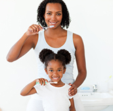 A mother and daughter brush their teeth together.