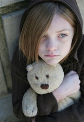 A sad girl holds her teddy bear