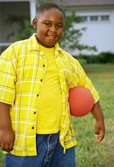 Child smiles and holds a dodge ball