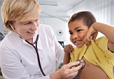A doctor listens to a young boy’s heart.