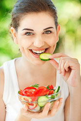 A woman eats a bowl of vegetables.