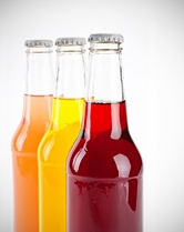 Three sodas, red, yellow, and orange, lined up together