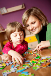 A mother helps her daughter with a puzzle.