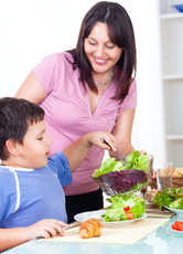 A mother serving salad to her son.