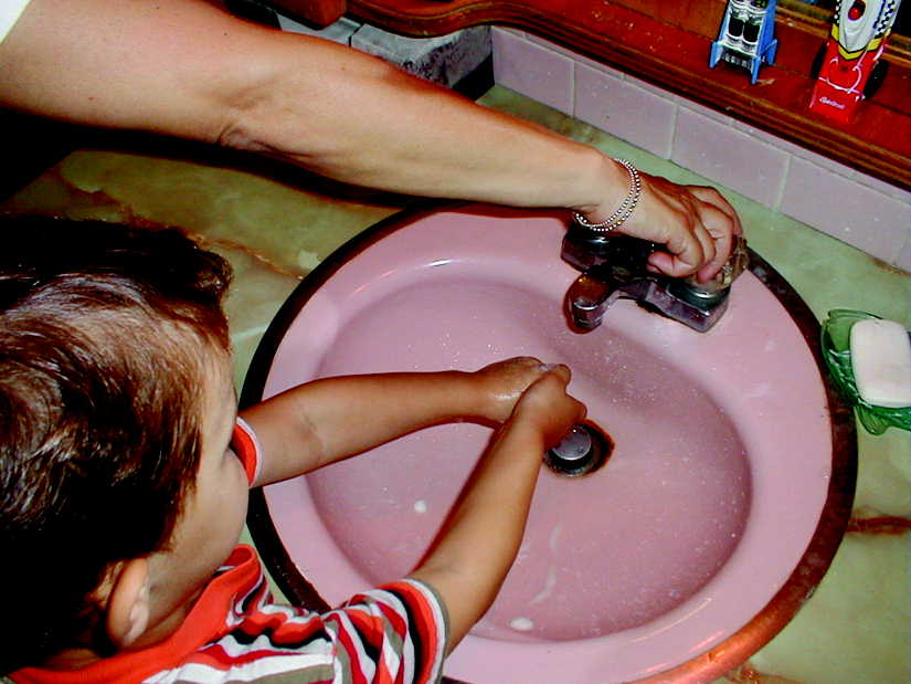 Mom and son at the bathroom sink making sure he washs his hands properly.