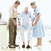 Two health care workers help an elderly man walk