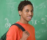 Photograph of a young African American man with a backpack on his shoulder, standing in front of a chalkboard.