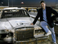 Photo of David Pogue leaning against a car with a NOVA logo on the car's hood.